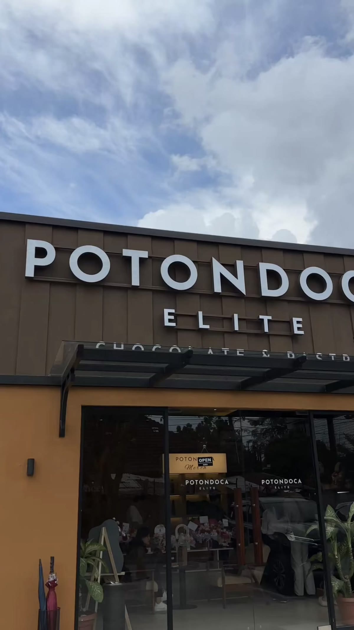 Fasad toko Potondoca Elite dengan signage cokelat